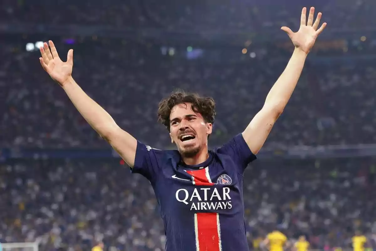 PSG player celebrating with arms raised in a stadium full of fans PSG player celebrating with arms raised in a stadium full of fans