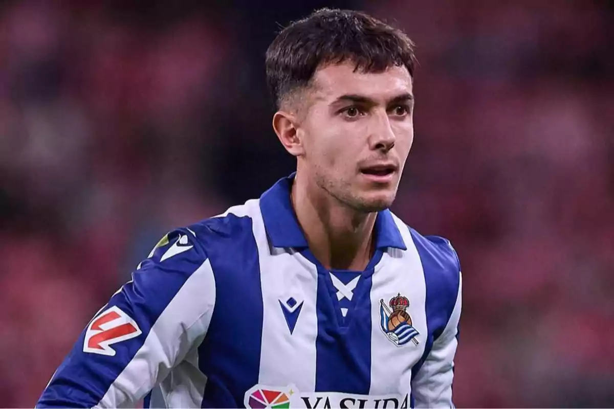 Jugador de fútbol con uniforme azul y blanco de la Real Sociedad durante un partido Jugador de fútbol con uniforme azul y blanco de la Real Sociedad durante un partido