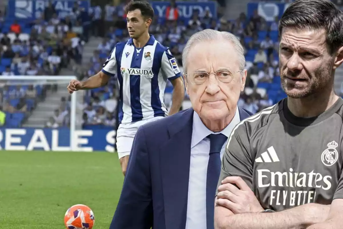 A Real Sociedad player on the field with two men in the foreground, one in a suit and the other in a Real Madrid training jersey.